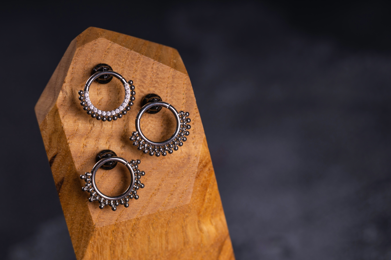 Beautiful piercing jewelry on wooden display.